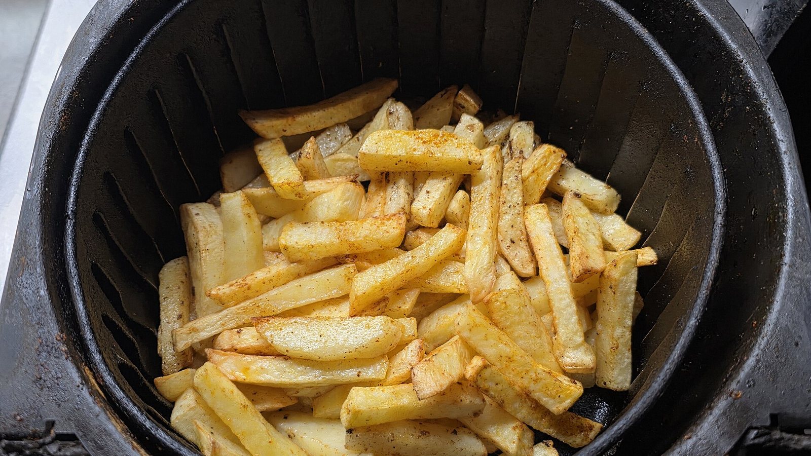 A single layer of french fries in a round air fryer basket