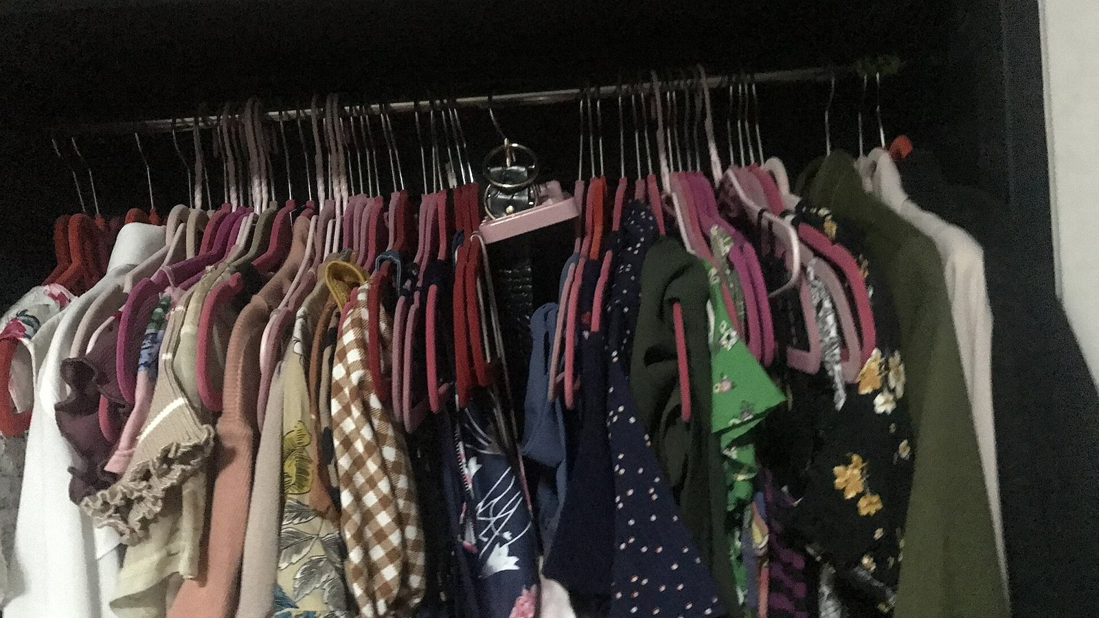 A closet rail packed with tops in mixed colors and prints on velvet hangers
